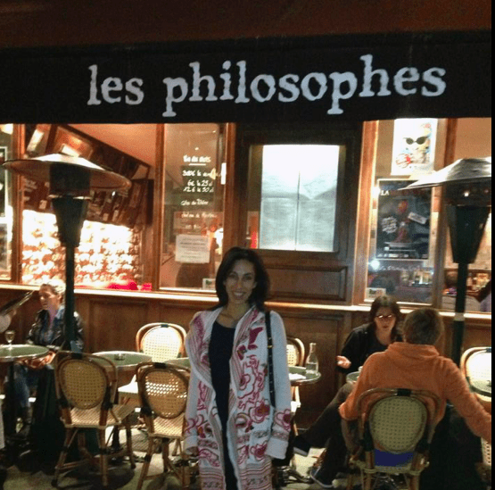 Woman standing under a banner that says "Les Philosophes".